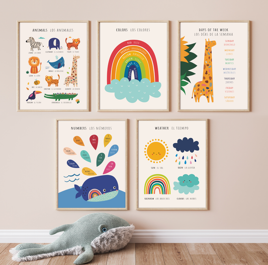 Five bilingual educational prints framed in light oak hanging on a pinkish wall featuring cute, colorful illustrations of animals, colors, days of the week, numbers and the weather labeled in English and Spanish. This bilingual display aids in language acquisition and cross-cultural learning and has the perfect aesthetic for a baby nursery, classroom, or other decor. 